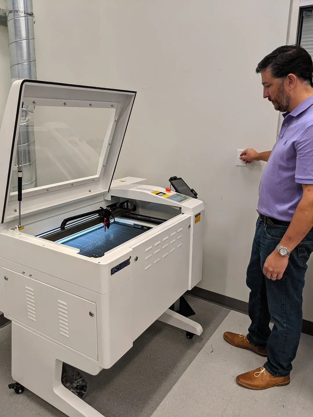 Teacher inspecting and repairing a 3d printer machine